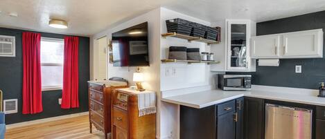 Una cocina compacta con microondas, lavavajillas y armarios de madera.