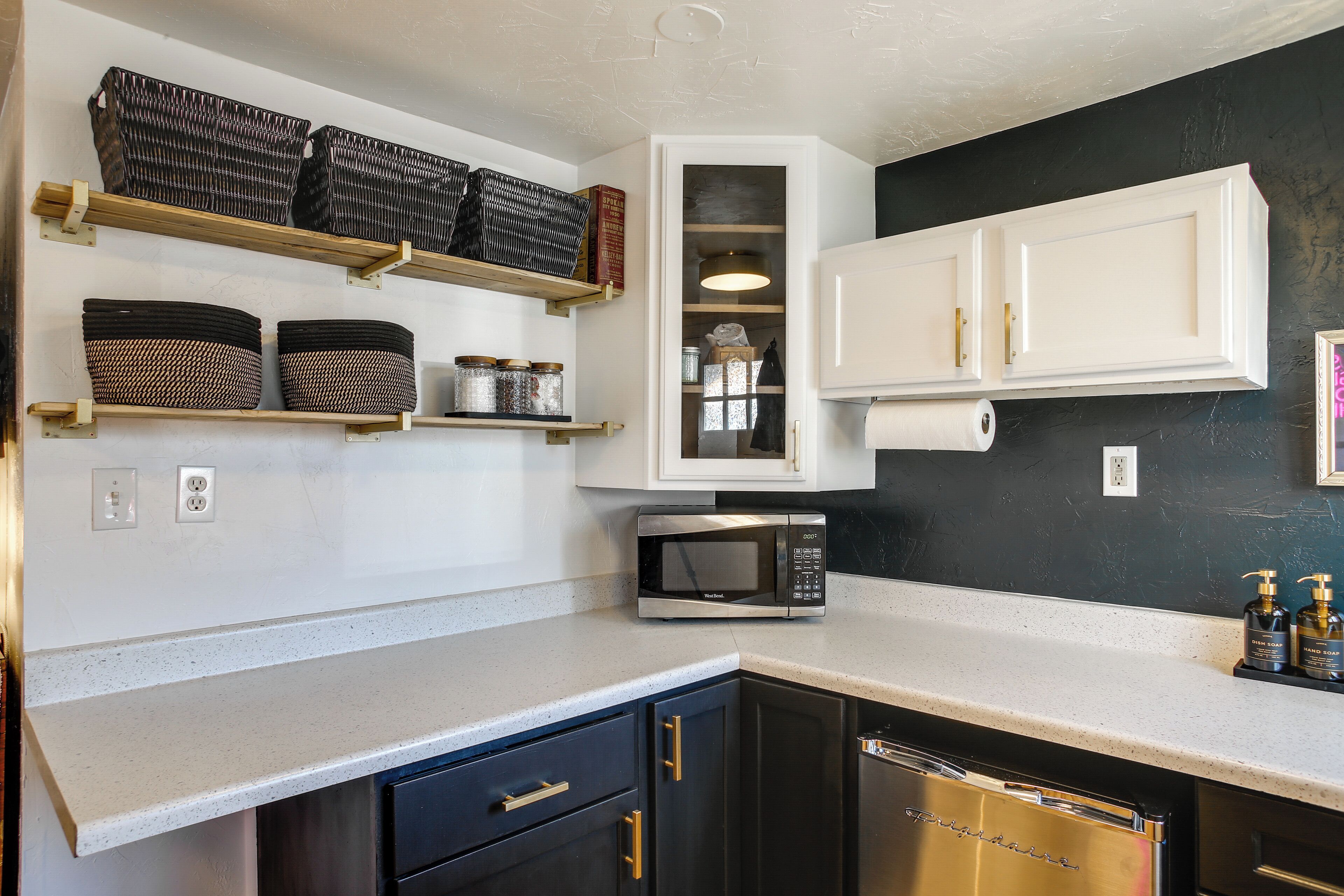 Cucina con mobili bianchi, microonde in acciaio inossidabile e lavastoviglie.