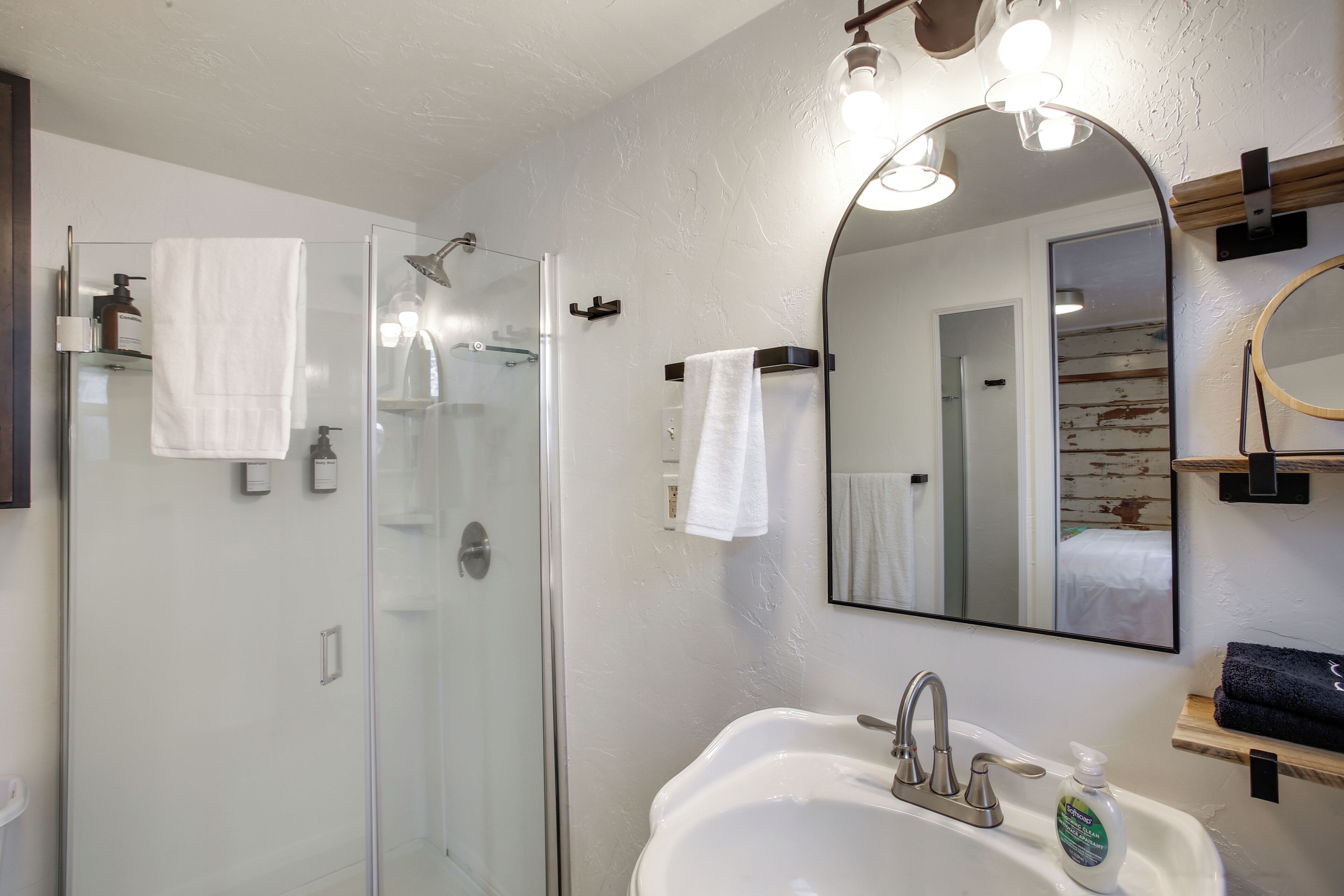 Une salle de bain moderne avec une douche à parois de verre, un lavabo blanc et un grand miroir.