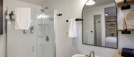 Une salle de bain moderne avec une douche à parois de verre, un lavabo blanc et un grand miroir.