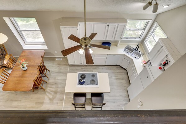 Una cocina moderna con una isla central, armarios blancos y un ventilador de techo.