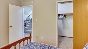 Un dormitorio con cama, una puerta de madera, un armario y una escalera que lleva a otra habitación.