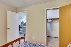 Un dormitorio con cama, una puerta de madera, un armario y una escalera que lleva a otra habitación.