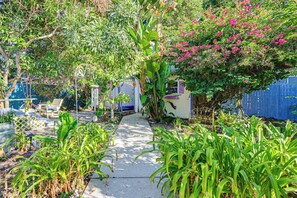 A pathway leading to a house with a blue fence, surrounded by various plants and a tree with pink flowers. - 4 Mi to Dtwn! Tranquil Tampa Getaway w/ 2 Decks (Tampa)