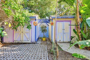 Ein Garten mit einem gepflasterten Weg, einem kleinen Baum und bunten Gartenhäusern.