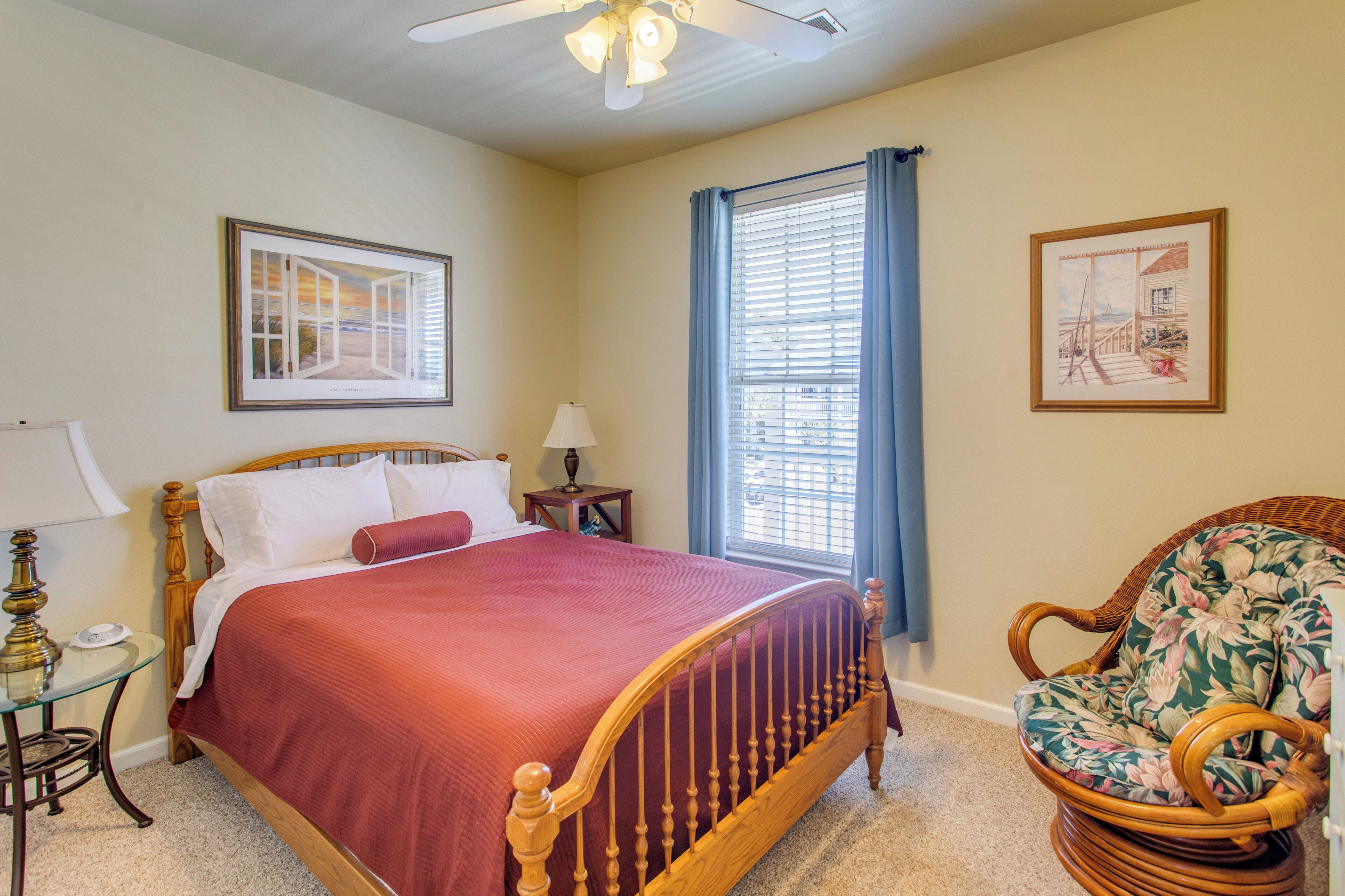 A bedroom with a bed, a chair, a lamp, a picture frame, and a window with curtains.