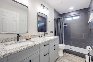 A bathroom with a granite countertop, a white sink, a mirror, a shower with a curtain, and a toilet. - (Jacksonville)