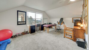 A room with a ceiling fan, a large window, a treadmill, a massage table, and a desk with a lamp. - Private Patio & Mtn Views: Drake Home on 5 Acres (Drake)
