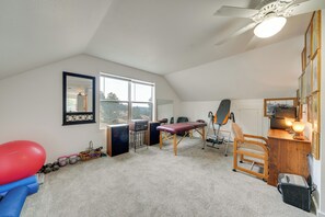 A room with a ceiling fan, a large window, a treadmill, a massage table, and a desk with a lamp. - Private Patio & Mtn Views: Drake Home on 5 Acres (Drake)