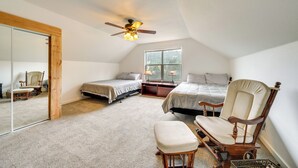A bedroom with two beds, a rocking chair, a wooden floor, a ceiling fan, and a large window. - Private Patio & Mtn Views: Drake Home on 5 Acres (Drake)