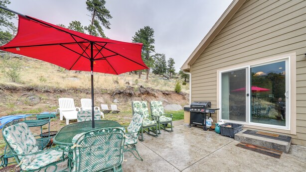 An outdoor patio with a table and chairs, a red umbrella, and a grill. - Private Patio & Mtn Views: Drake Home on 5 Acres (Drake)