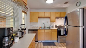 Una cocina moderna con armarios de madera, electrodomésticos de acero inoxidable y una cafetera.