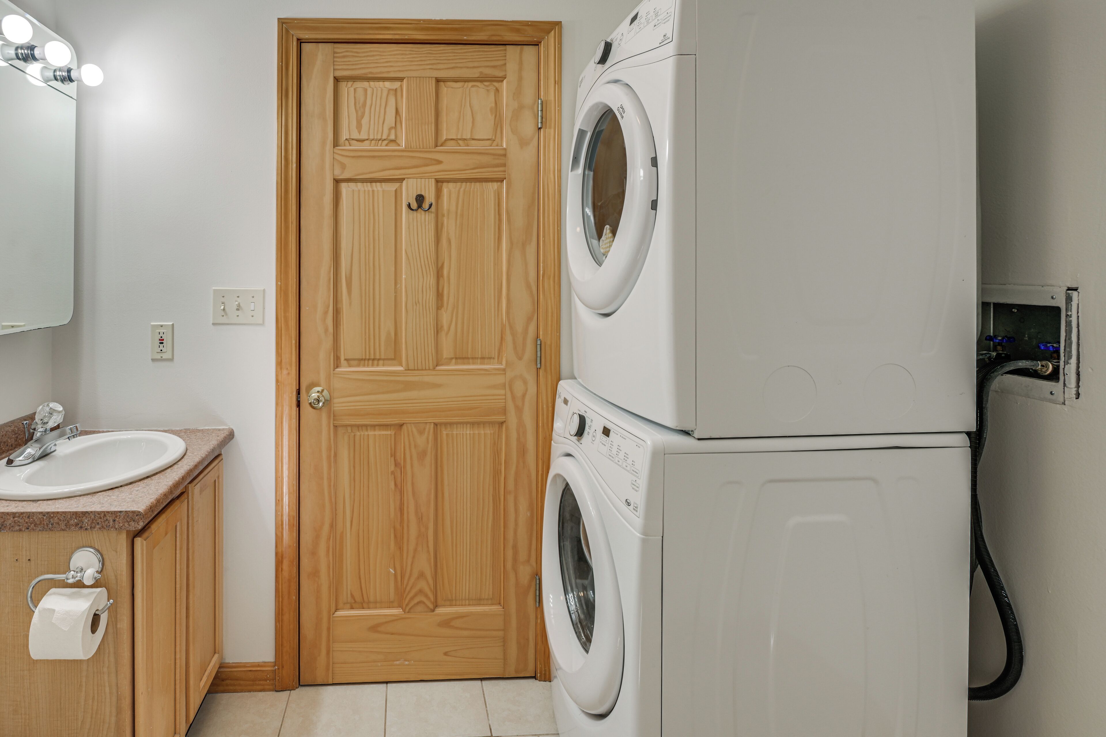 A laundry room with a wooden door, a washing machine, and a sink with a countertop.