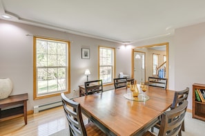 A dining area with a wooden table, chairs, and a view of the outdoors through large windows. - 4 Mi to Acadia Trails! Coastal Maine Launchpad (Mount Desert)