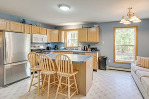 A kitchen with wooden cabinets, a stainless steel refrigerator, a microwave, a stove, and two wooden bar stools. - 4 Mi to Acadia Trails! Coastal Maine Launchpad (Mount Desert)