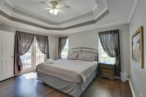 Ein Schlafzimmer mit einem Bett, Vorhängen, einem Deckenventilator und einem Fenster.