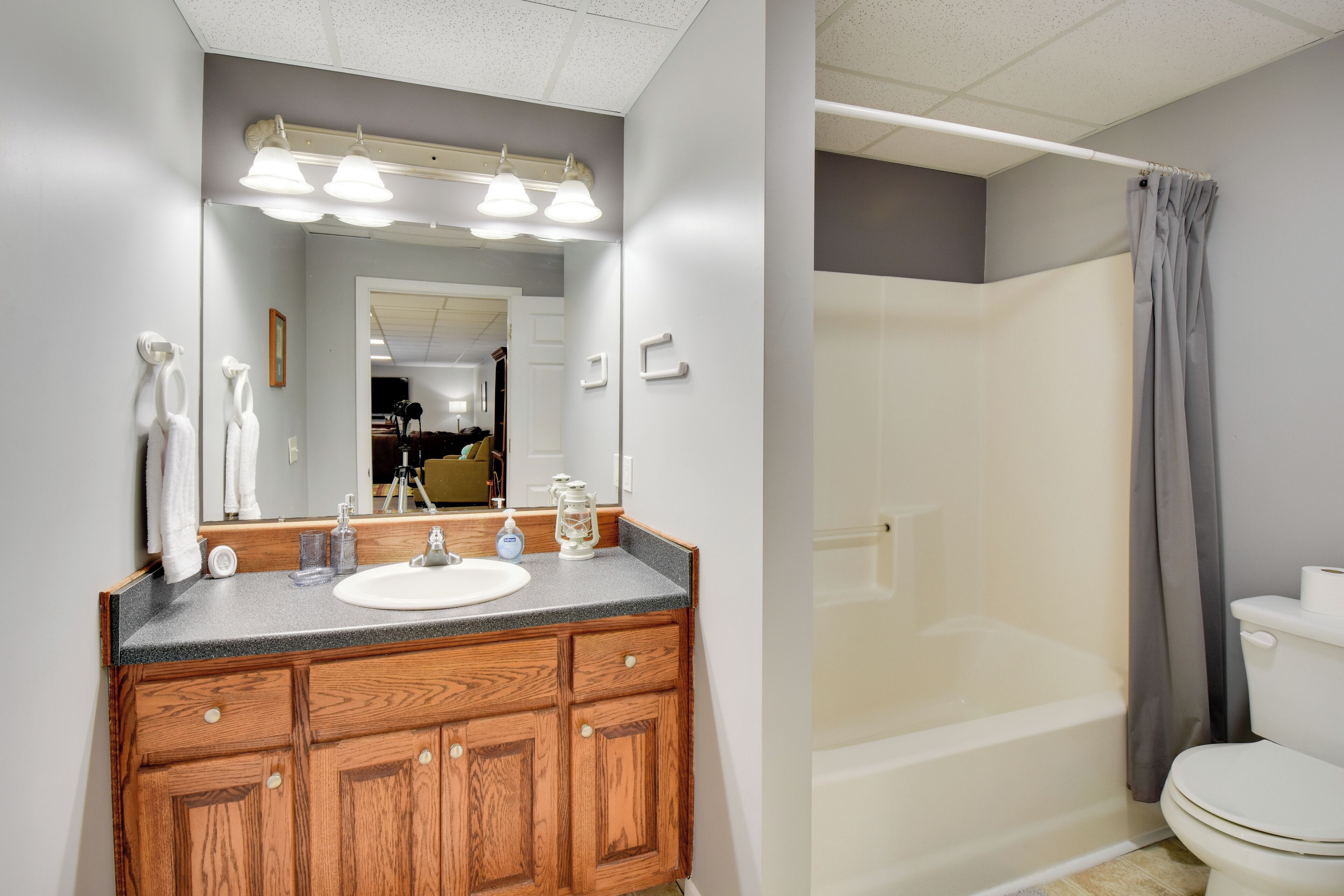 A bathroom with a wooden vanity, a mirror, a sink, and a shower area.