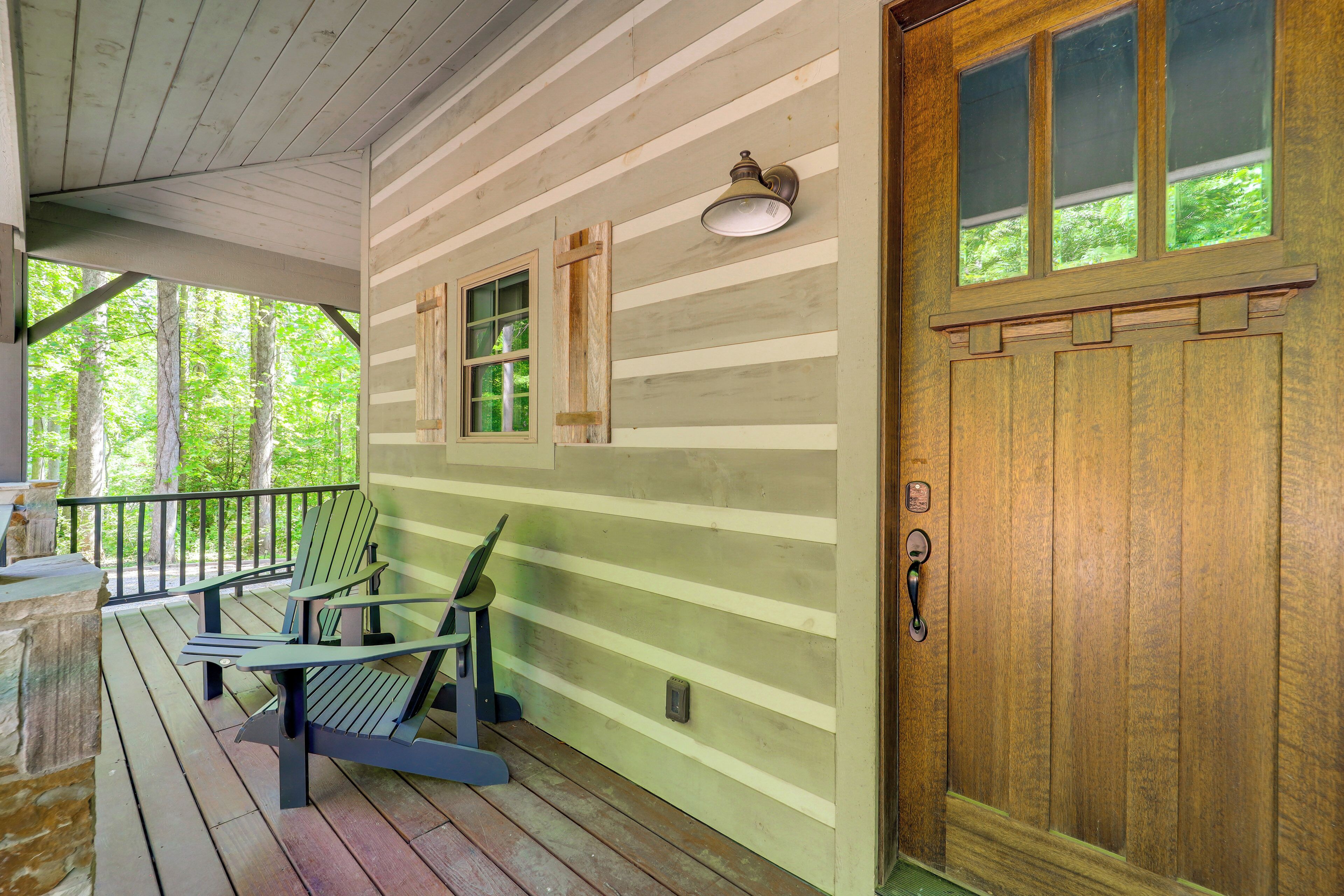 Un portico in legno con poltrone Adirondack, una porta in legno con pannelli di vetro e una finestra con cornice in legno.