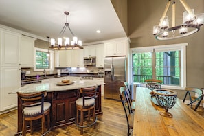 Una cocina amplia con una isla grande, electrodomésticos de acero inoxidable y vistas al exterior.