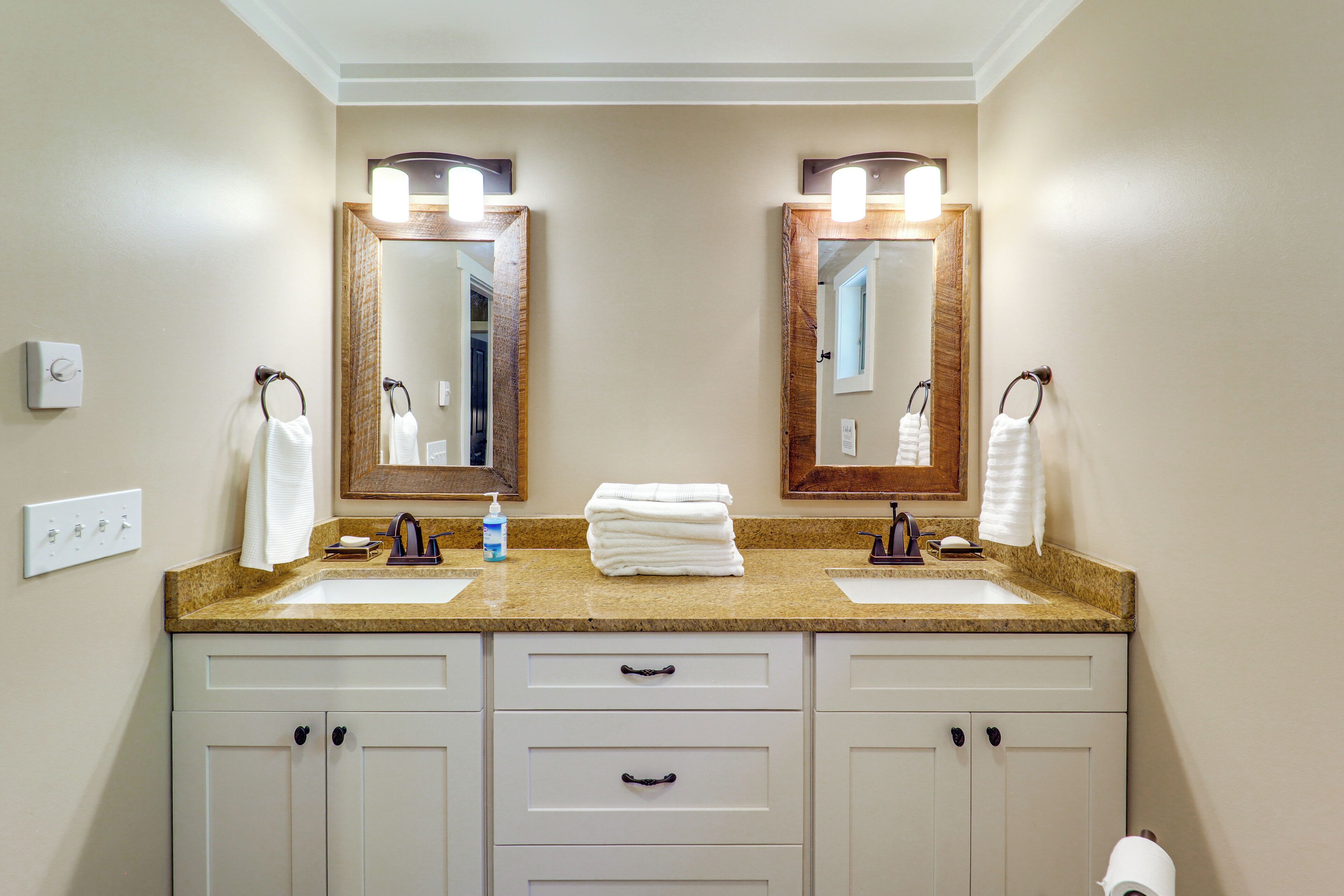 A bathroom with two sinks, a mirror, and a towel rack.