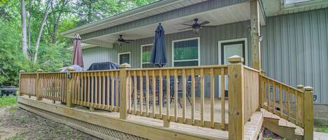 A wooden deck with a railing, a covered porch area, and a garage door.