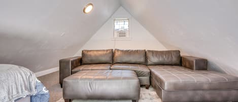 Dormitorio tipo loft con sofá seccional, una ventana pequeña y una lámpara de techo.