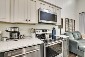A modern kitchen with white cabinetry, a stainless steel microwave, a coffee maker, and a gas stove. - Creekside Compound in Wildwood: Hot Tub & Fire Pit (Wildwood)
