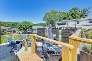 A deck with outdoor furniture, a covered grill area, and a view of a large RV.