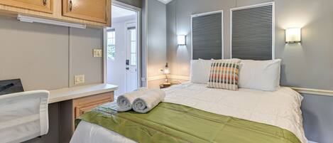 A bedroom with a bed, a desk, and a chair.
