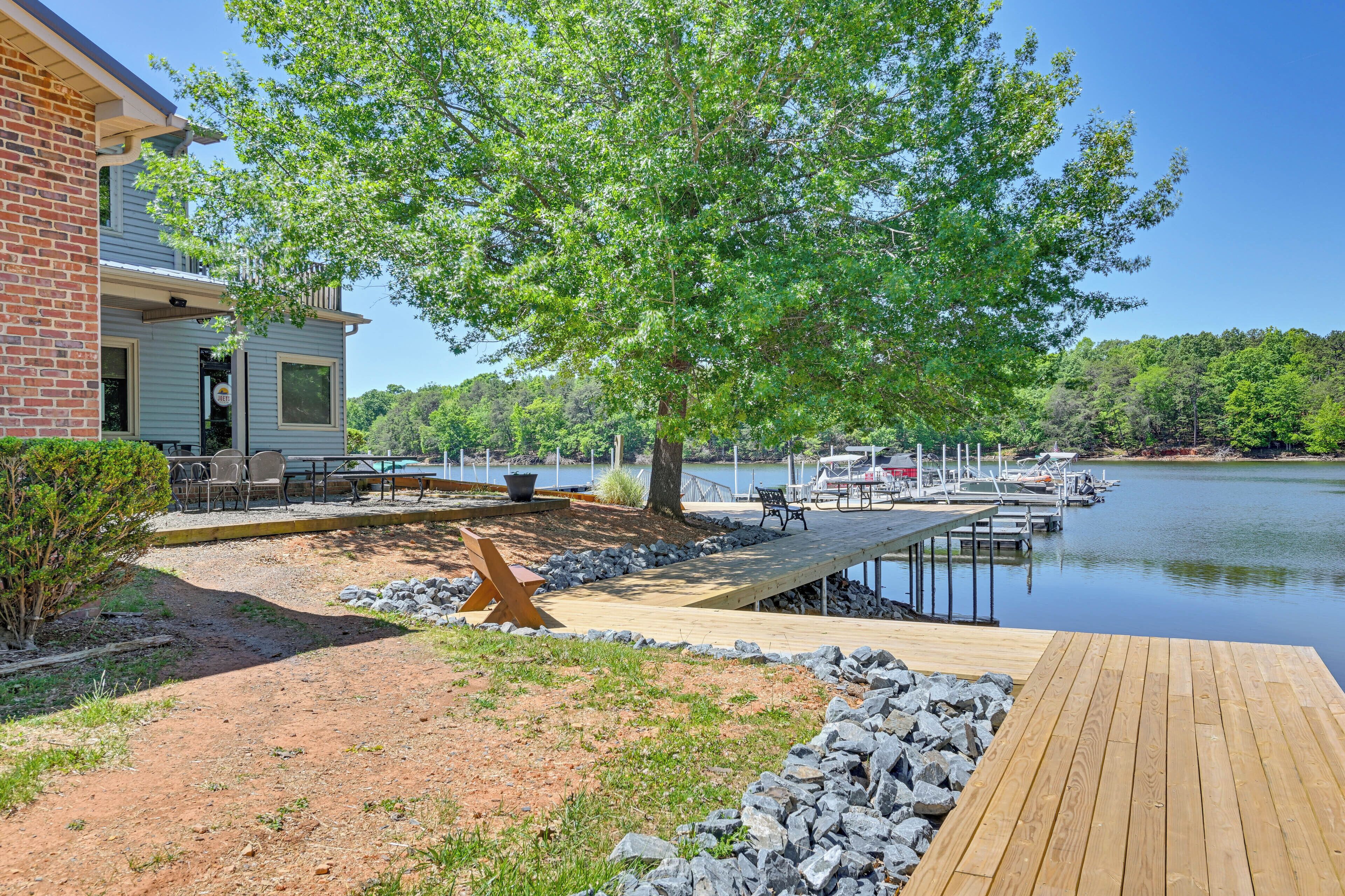 A lakeside property with a dock, outdoor seating, and a building with a balcony.