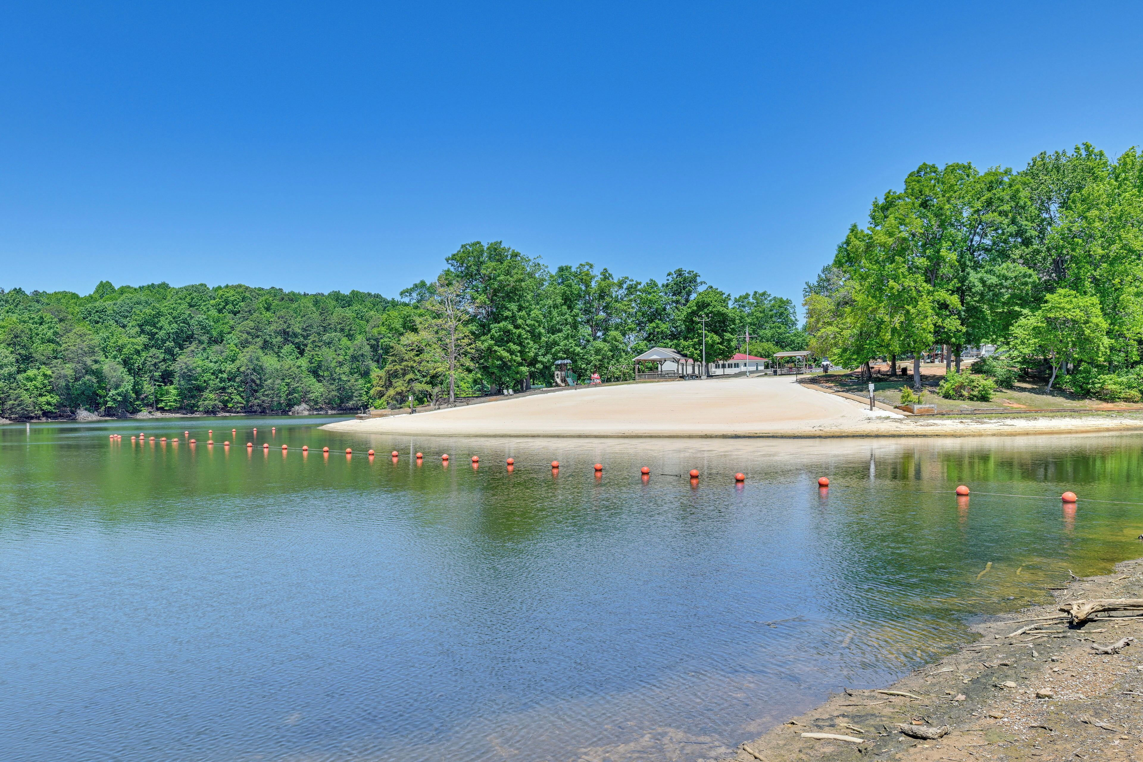 Un lac bordé d’une plage de sable, entouré d’une forêt dense et verdoyante.