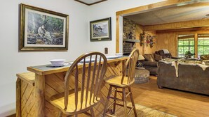 A wooden dining area with chairs, a table, and framed artwork on the walls. - Fire Pit, Patio, Views! Group Lodge in Cheaha Mtns (Delta)