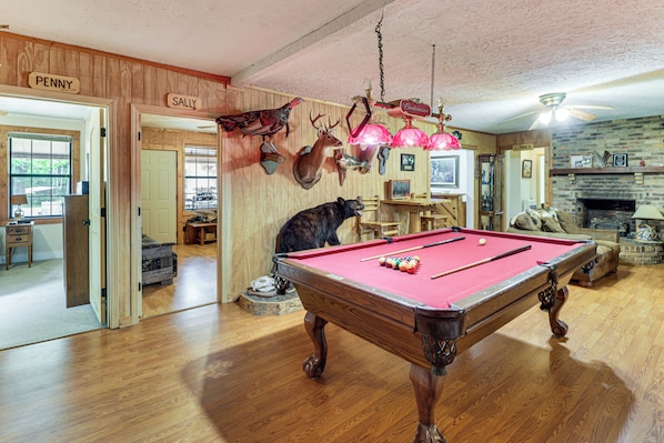 A pool table with a red felt surface, surrounded by wooden walls with mounted animal heads. - Fire Pit, Patio, Views! Group Lodge in Cheaha Mtns (Delta)
