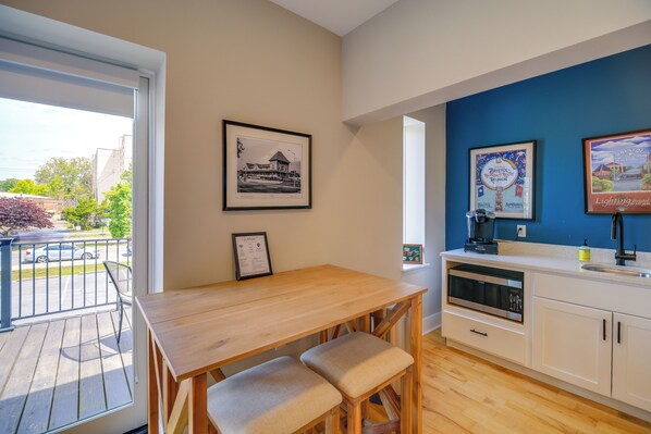 Una cocina moderna con una mesa y un banco de madera, un microondas y un lavamanos.