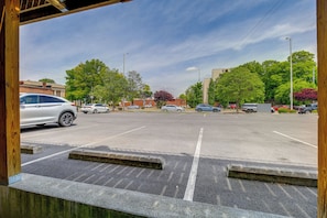 Um estacionamento com vários carros, árvores e edifícios ao fundo.