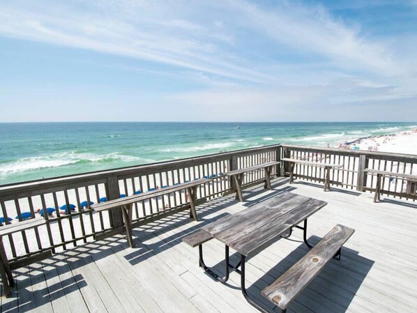 Eine Holzterrasse mit Bänken, die auf einen Strand blickt.