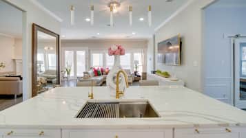 A spacious kitchen with a large island, modern fixtures, and a view into the living area.