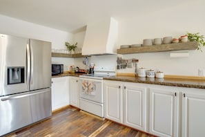 Una cocina moderna con armarios blancos, electrodomésticos de acero inoxidable y piso de madera.