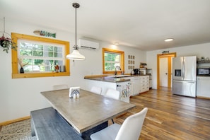 A modern kitchen with a dining area, wooden flooring, and a large window.