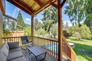 A covered outdoor deck with a pool, wooden furniture, and a view of a forested area. - Mount Rainier Views & Hot Tub: Pet-friendly Cabin! (Mineral)