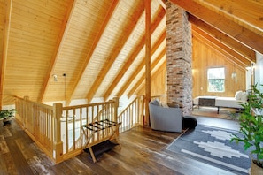 A spacious loft with a wooden ceiling, a brick fireplace, a staircase, and a cozy seating area. - Mount Rainier Views & Hot Tub: Pet-friendly Cabin! (Mineral)