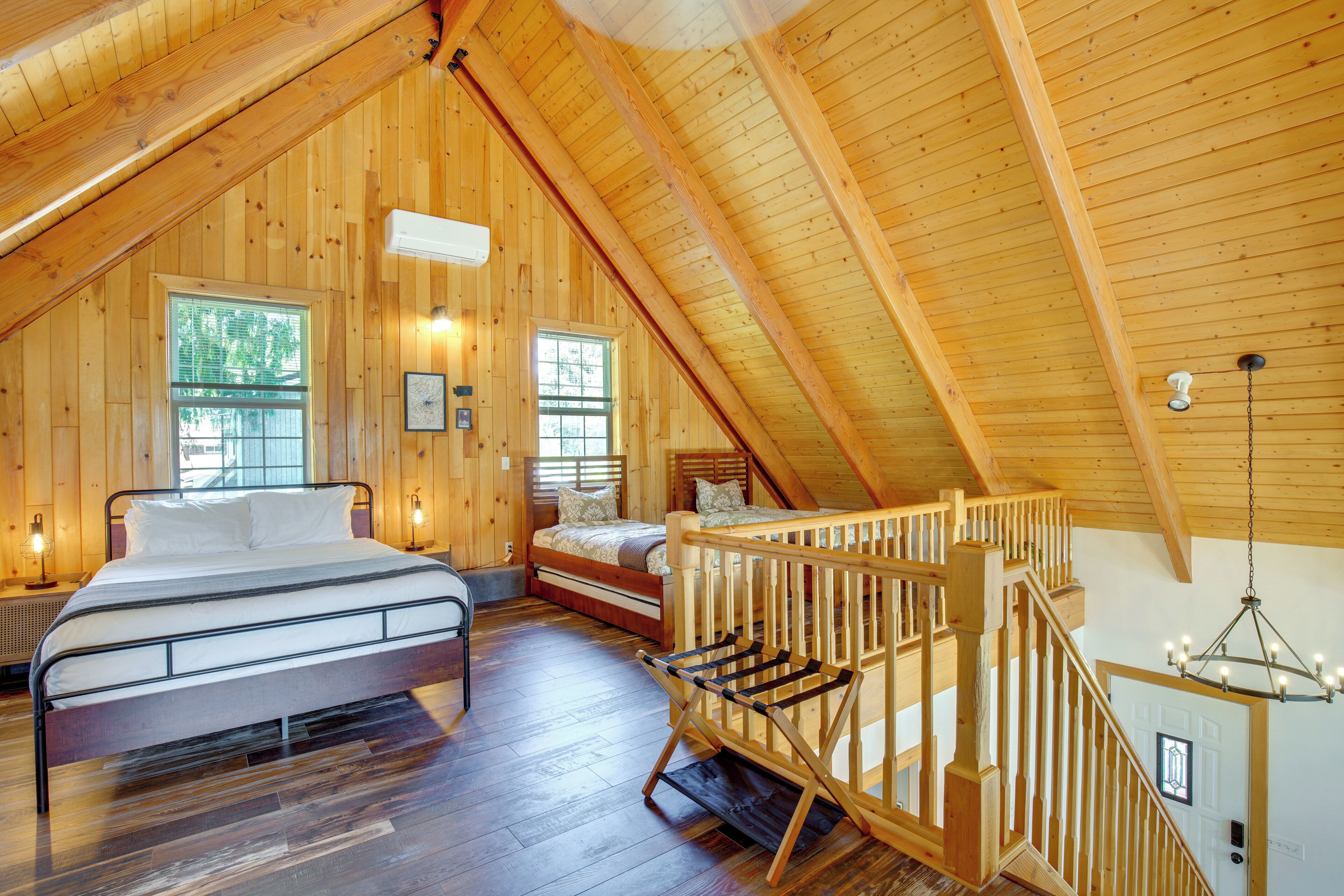 Uma cabana de madeira com quarto no mezanino, escada e lustre.