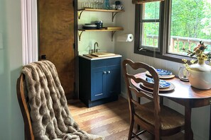 Eine Küche mit einem Holztisch, Stühlen, einer Spüle und Regalen über der Arbeitsfläche.