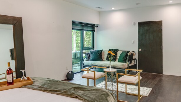 A modern bedroom with a bed, bedside table, and a window with blinds. - Hike, Boat & Explore! Serene Stafford Apt w/ Patio (Stafford)