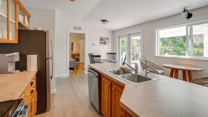 A modern kitchen with a dishwasher, a refrigerator, a sink, and wooden cabinets.