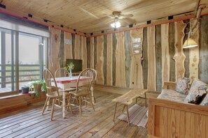 A wooden interior with a dining table, chairs, a sofa, and a ceiling fan. - Hike, Soak + Play: Rustic Maysville Escape! (Maysville)