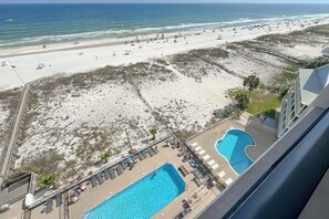 Ein Hotel mit Pool, Meerblick und einem eingezäunten Bereich mit Liegestühlen.