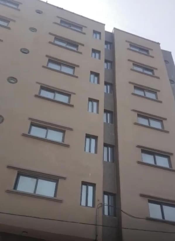 A multi-story building with a beige facade, rectangular windows, and a central vertical structure. - Apparently on vacation or business in DAKAR SENEGAL (Dakar)