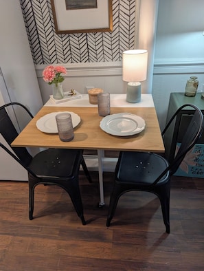 A dining table with two chairs, a vase with flowers, a candle, and a lamp. - Thoughtfully design retreat created for rest, renewal, and meaningful connection (Banner Elk)