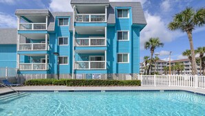 Un hôtel à plusieurs étages doté de balcons, d’une piscine et de palmiers.